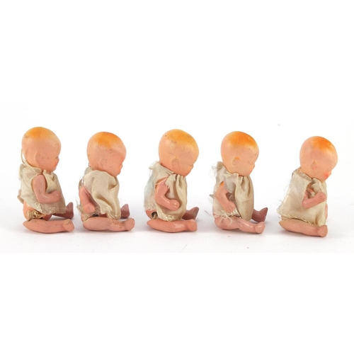 3310 - Five hand painted bisque porcelain dolls with articulated limbs, housed in a basket, each 7.5cm high