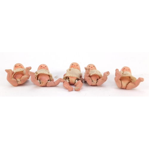 3310 - Five hand painted bisque porcelain dolls with articulated limbs, housed in a basket, each 7.5cm high