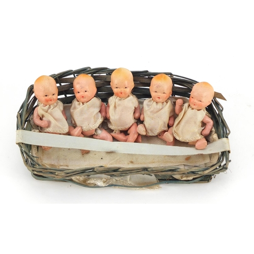 3310 - Five hand painted bisque porcelain dolls with articulated limbs, housed in a basket, each 7.5cm high