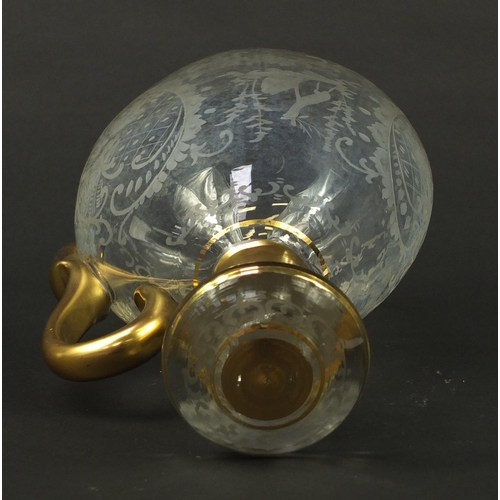 3920 - Continental glass decanter with gilt handle etched with a stag, buildings and flowers, 22.5cm high