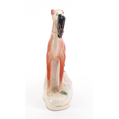 1179 - Staffordshire pottery whippet with game, 19cm high