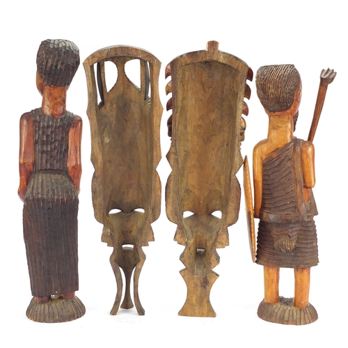 1507 - Four tribal wood carvings including a tribesman and two face masks, the largest 60cm high