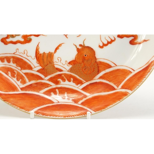 124 - Chinese porcelain shallow dish hand painted in iron red with a dragon amongst clouds and fish in wat... 