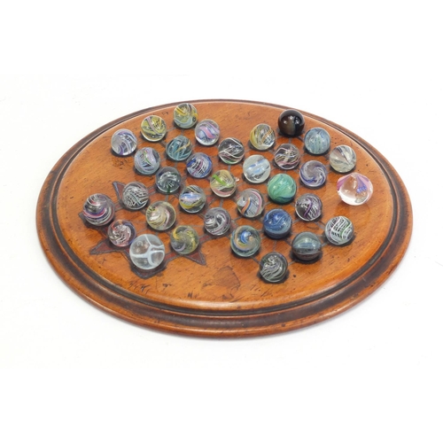 713 - 19th century solitaire board and a selection of mostly swirl marbles, the board 19.5cm in diameter