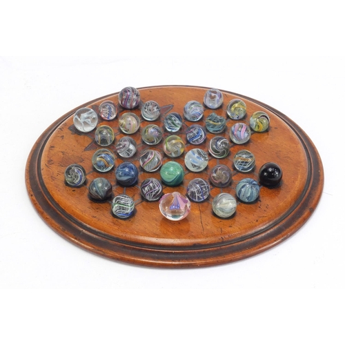 713 - 19th century solitaire board and a selection of mostly swirl marbles, the board 19.5cm in diameter