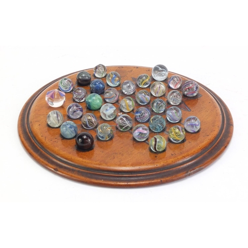 713 - 19th century solitaire board and a selection of mostly swirl marbles, the board 19.5cm in diameter