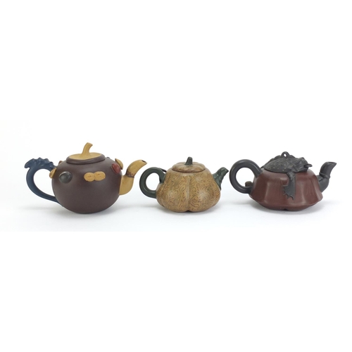 129 - Three Chinese Yixing terracotta teapots including a toad design example, each with impressed charact... 