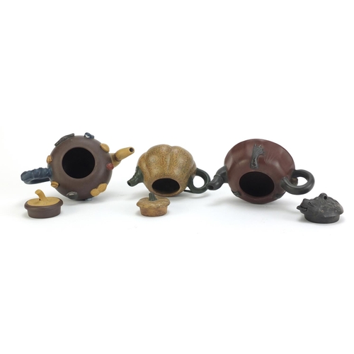 129 - Three Chinese Yixing terracotta teapots including a toad design example, each with impressed charact... 