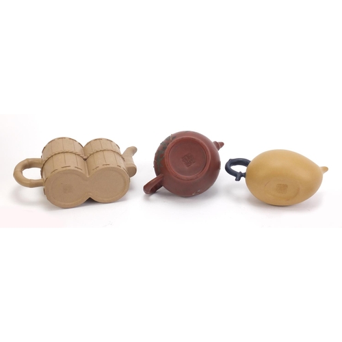 835 - Three Chinese Yixing teracotta teapots including one in the form of a yellow peach and another hand ... 