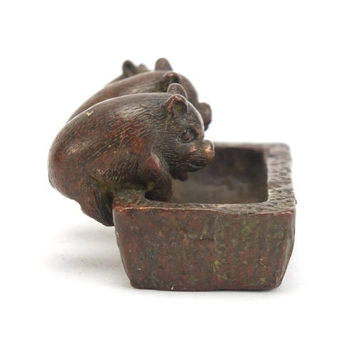 636 - Japanese patinated bronze okimono of three piglets in a trough, impressed character marks to the bas... 