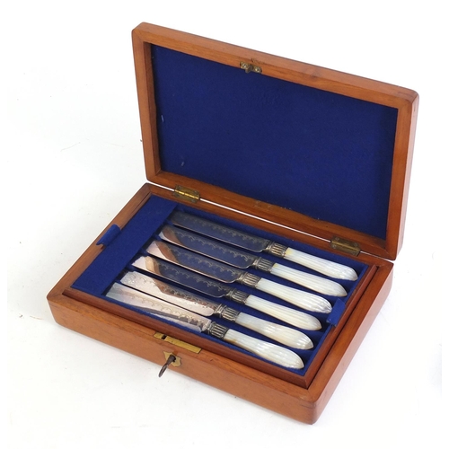 822 - Set of six silver plated cake knives and forks with mother of pearl handles, housed in a fitted waln... 