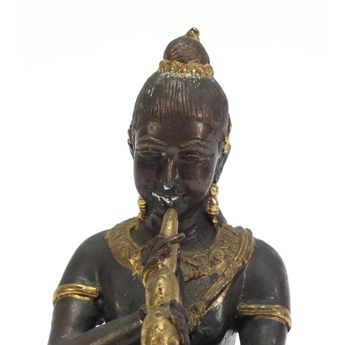 888 - Asian partially gilt bronze figure of a female playing a flute, 15cm high