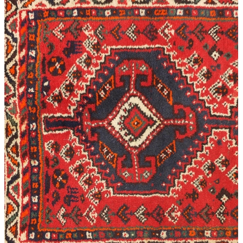 1598 - Rectangular Persian rug having an all over geometric floral design onto a red ground, 123cm x 80cm