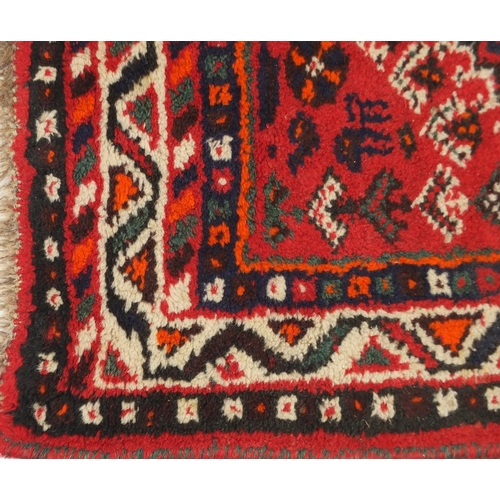 1598 - Rectangular Persian rug having an all over geometric floral design onto a red ground, 123cm x 80cm