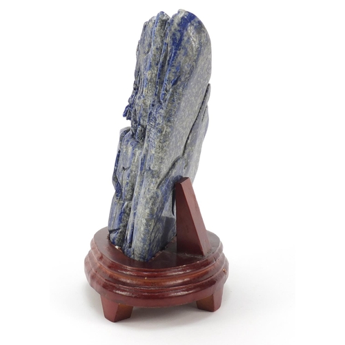 135 - Large Chinese lapis lazuli fragment carved with a figure amongst mountains beside a tree raised on a... 