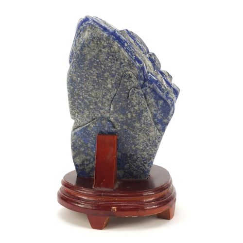 135 - Large Chinese lapis lazuli fragment carved with a figure amongst mountains beside a tree raised on a... 