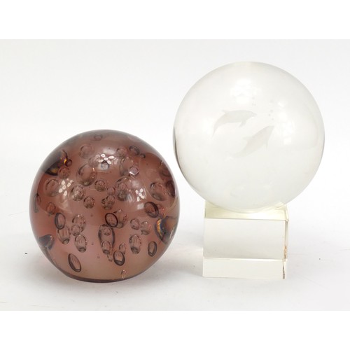 941 - Two large glass paperweights including one with two dolphins on stand, each 14cm in diameter