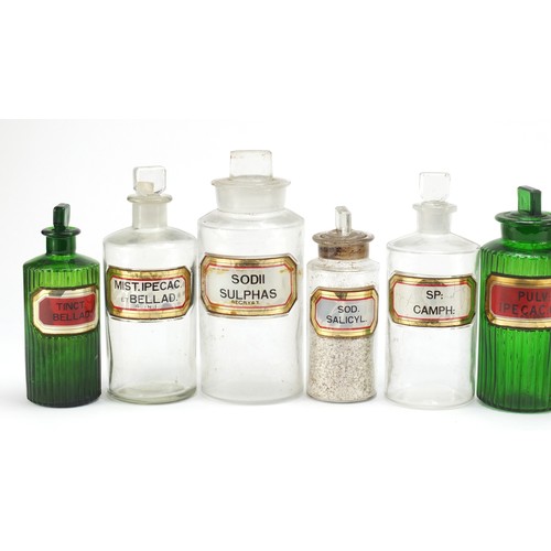 74 - Antique glass apothecary jars with labels including three green examples, the largest 22cm high