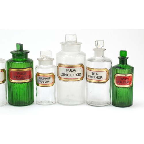 74 - Antique glass apothecary jars with labels including three green examples, the largest 22cm high