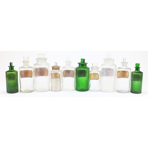 74 - Antique glass apothecary jars with labels including three green examples, the largest 22cm high