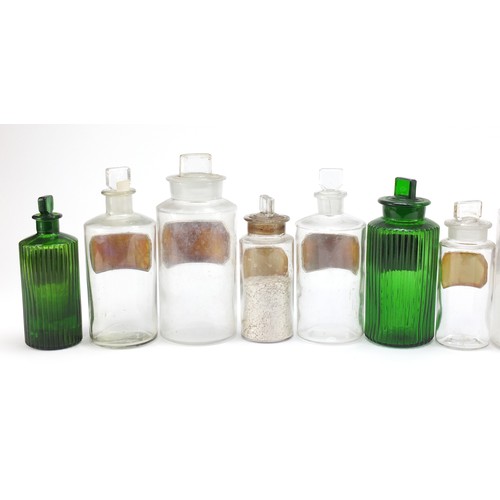 74 - Antique glass apothecary jars with labels including three green examples, the largest 22cm high