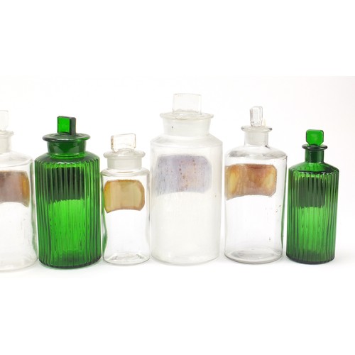 74 - Antique glass apothecary jars with labels including three green examples, the largest 22cm high