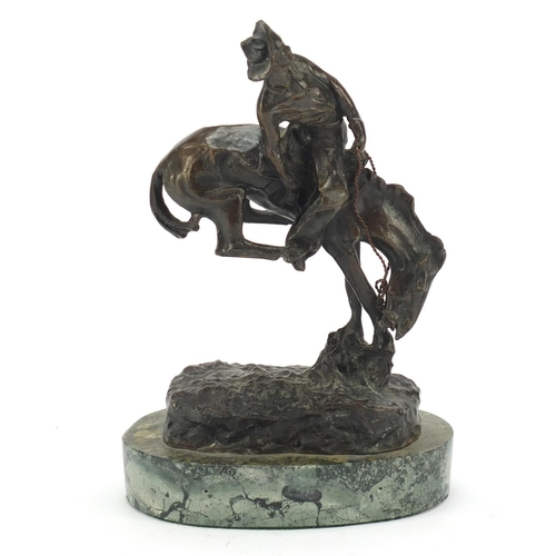 492 - Patinated bronze figure of a cowboy on horseback in the style of Frederick Remington, raised on an o... 