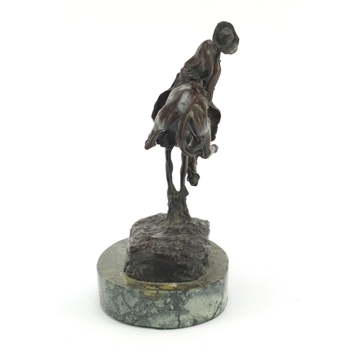 492 - Patinated bronze figure of a cowboy on horseback in the style of Frederick Remington, raised on an o... 