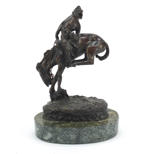 492 - Patinated bronze figure of a cowboy on horseback in the style of Frederick Remington, raised on an o... 