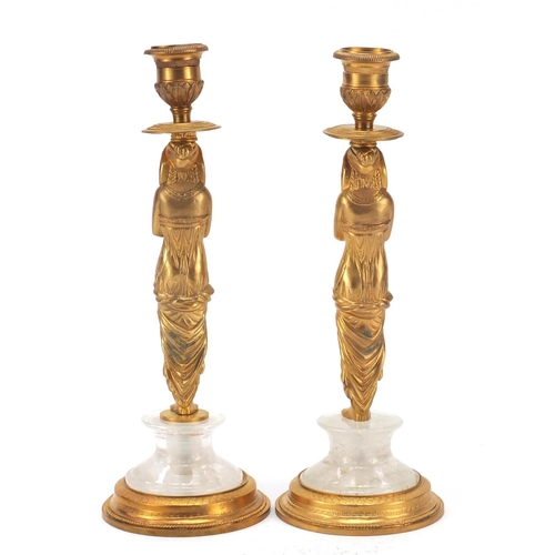 114 - Pair of French Empire style Egyptian revival gilt bronze and rock crystal candlesticks, each 25cm hi... 