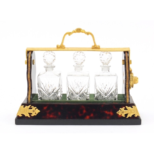 290 - Gilt metal and boulle style tantalus with three cut glass decanters, 26.5cm wide