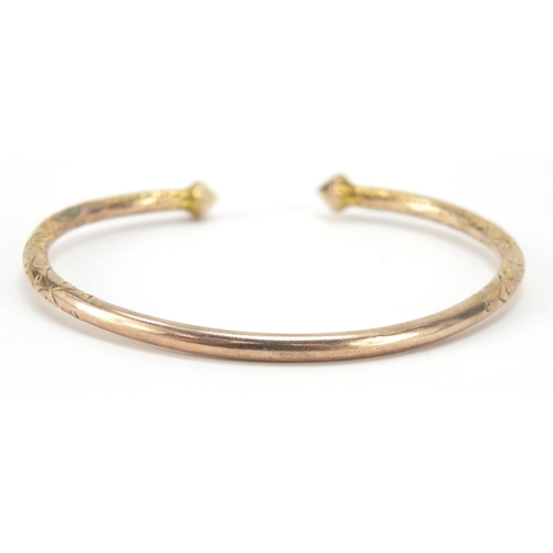 183 - Unmarked gold bangle, (tests as 9ct gold) engraved with flowers, 7cm wide, 21.8g