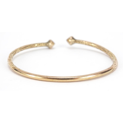 270 - Unmarked gold bangle, (tests as 9ct gold) engraved with flowers, 7cm wide, 23.2g