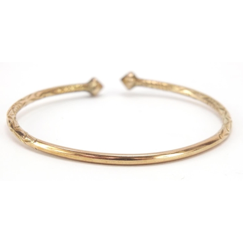 138 - Unmarked gold bangle, (tests as 9ct gold) engraved with flowers, 7cm wide, 22.2g