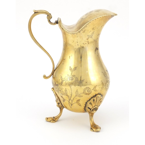 320 - Silver gilt water jug with hinged lid, the body engraved with flowers and raised on three hoof feet,... 