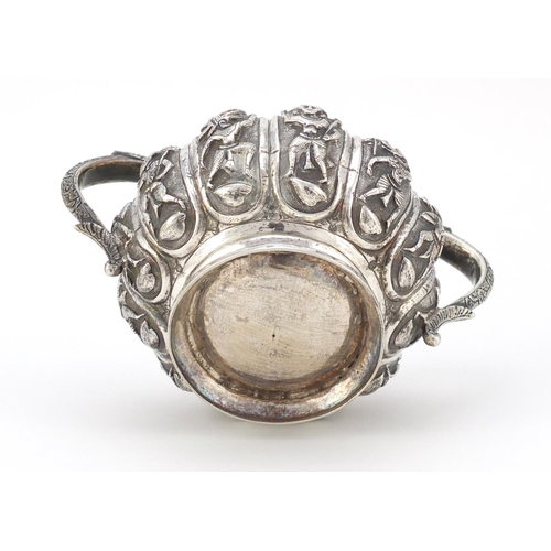 166 - Indian unmarked silver twin handled sugar bowl, embossed with mythical figures, 14cm wide, 245.0g