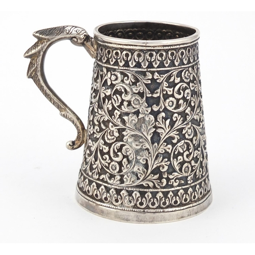 165 - Indian unmarked silver tankard of conical form, profusely embossed with flowers and foliage, 9cm hig... 