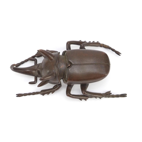 153 - Japanese patinated bronze rhinoceros beetle, impressed character marks to the underside, 10cm in len... 