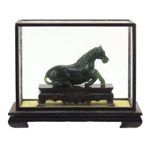 1550 - Chinese green horse, possibly hardstone, housed in a glazed case, overall 17cm H x 21cm W x 11cm D