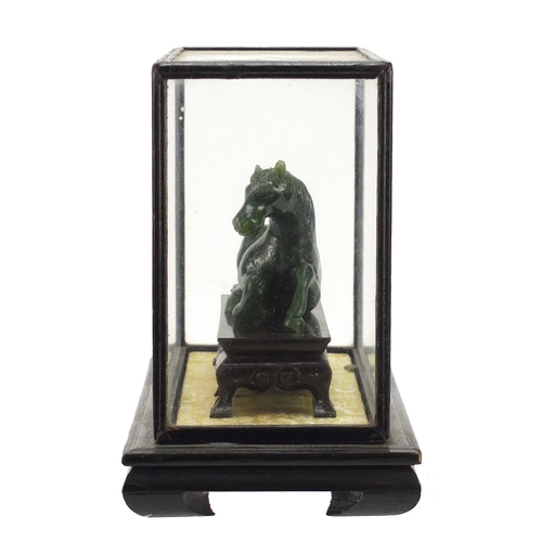 1550 - Chinese green horse, possibly hardstone, housed in a glazed case, overall 17cm H x 21cm W x 11cm D