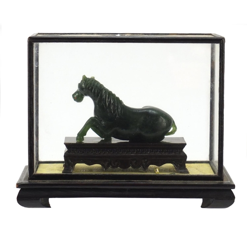 1550 - Chinese green horse, possibly hardstone, housed in a glazed case, overall 17cm H x 21cm W x 11cm D