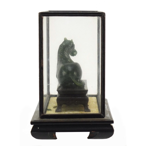 1550 - Chinese green horse, possibly hardstone, housed in a glazed case, overall 17cm H x 21cm W x 11cm D