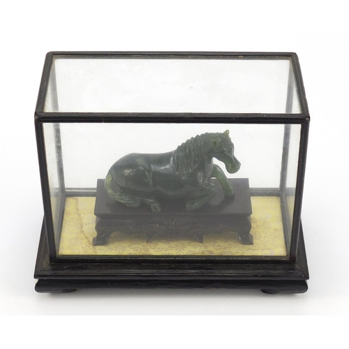 1550 - Chinese green horse, possibly hardstone, housed in a glazed case, overall 17cm H x 21cm W x 11cm D