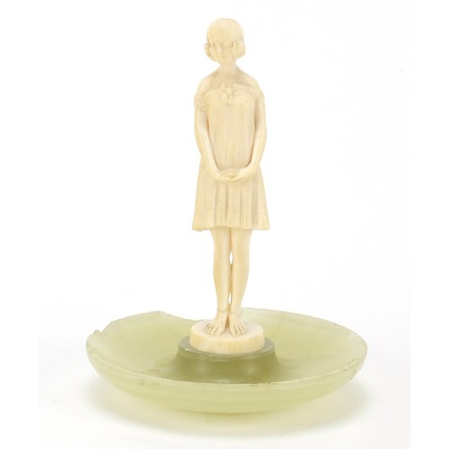 129 - Art Deco carved ivory figure of a young girl mounted on an onyx dish, 13cm high