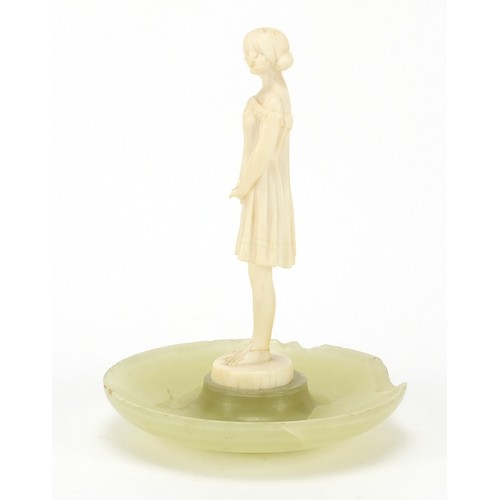 129 - Art Deco carved ivory figure of a young girl mounted on an onyx dish, 13cm high