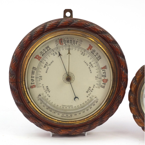 121 - Two carved oak rope twist design wall barometers, the largest 27cm in diameter