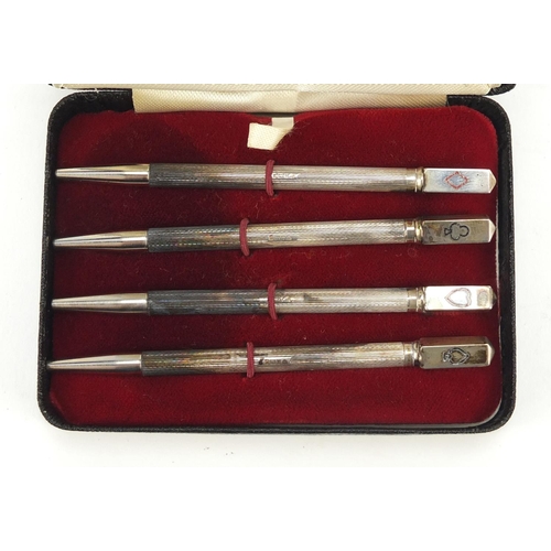 314 - Set of four silver bridge pencils with suit motifs and case, Birmingham 1947, each 9cm in length