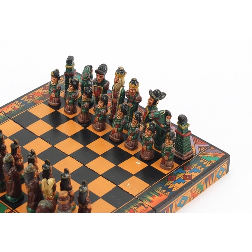 751 - Hand painted terracotta Aztec design folding chess set with board, the largest piece 6.5cm high