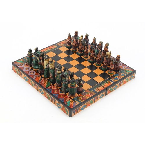 751 - Hand painted terracotta Aztec design folding chess set with board, the largest piece 6.5cm high