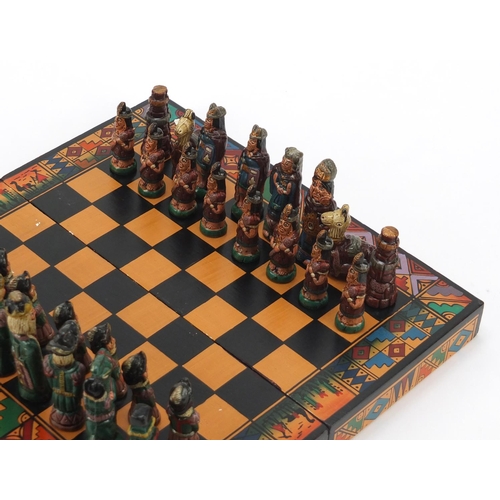 751 - Hand painted terracotta Aztec design folding chess set with board, the largest piece 6.5cm high